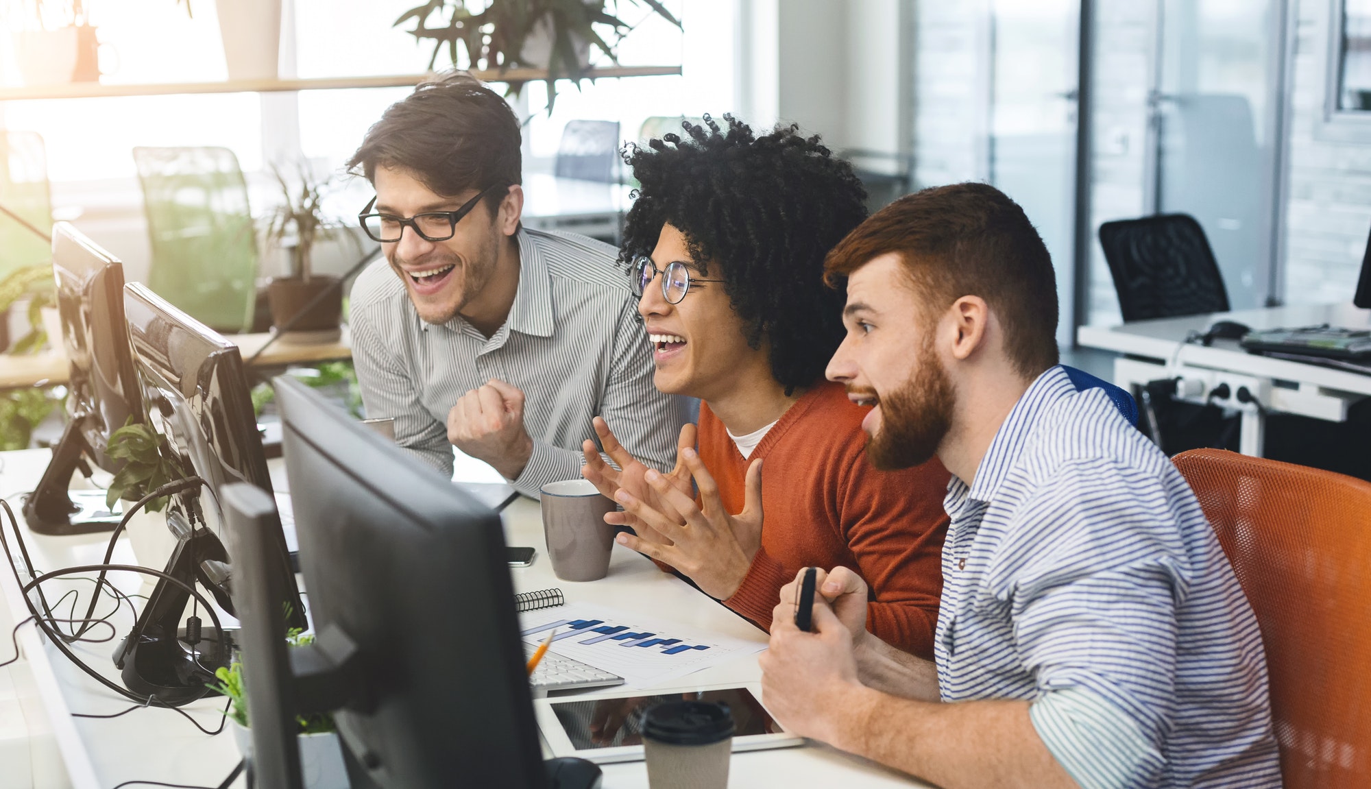 Three young men enjoying good coding job on computer